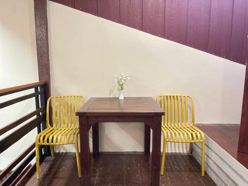 a table with two chairs and a vase with flowers at The Memory Hostel in Trat