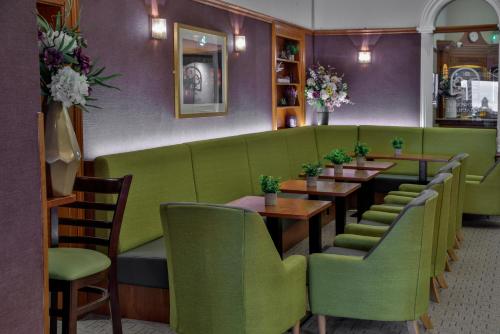 a restaurant with green booths and wooden tables at Invercarse Hotel Dundee, BW Signature Collection in Dundee