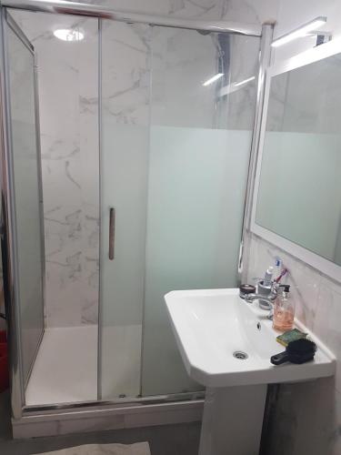 La salle de bains est pourvue d'une douche et d'un lavabo blanc. dans l'établissement CHAMBRE INDIVIDUELLE CHEZ SANDRINE A 20 min des Portes de PARIS, à Saint-Gratien