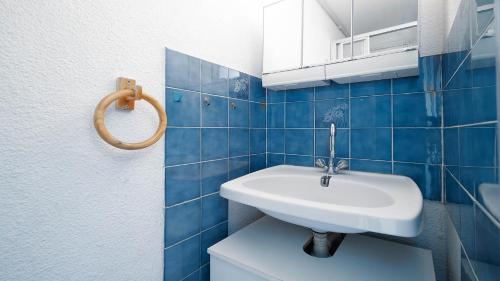 La salle de bains est pourvue d'un lavabo blanc et de carrelage bleu. dans l'établissement Mer et Soleil C N143 - ST4, au Cap d'Agde