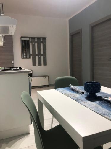 a kitchen with a white table and green chairs at Affitti brevi TAORMINA in Realmonte