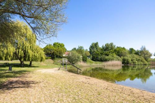 a park with a playground next to a lake at Beautiful holiday home on park on swimming water in Ewijk