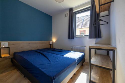 a blue bedroom with a bed and a window at Beautiful holiday home on park on swimming water in Ewijk