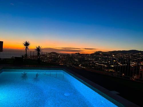 a swimming pool on the roof of a building with a sunset at Villa Amazing View Funchal - Lux & Pool in Funchal