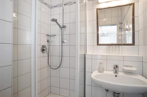 a white bathroom with a shower and a sink at Hotel Garni Vitamari in Wasserburg am Bodensee