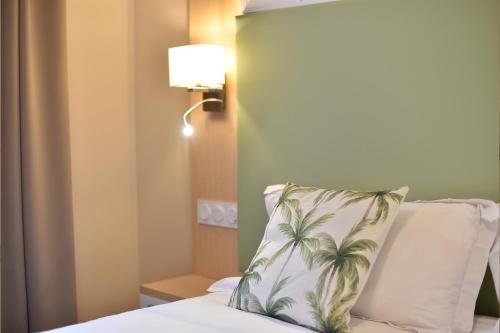 a hotel room with a bed with a palm tree pillow at Résidence Saint-Jean in Saint-Florent
