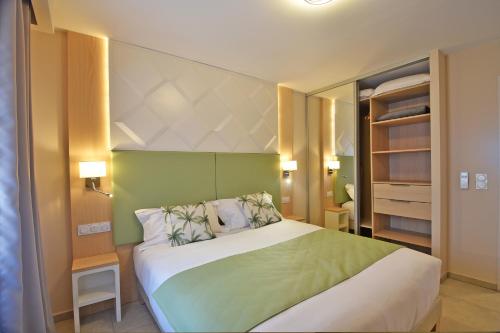 a bedroom with a large bed with a green headboard at Résidence Saint-Jean in Saint-Florent