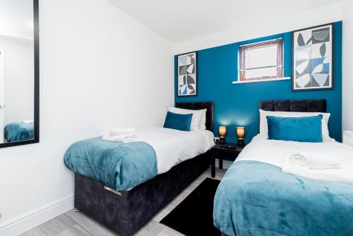 zwei Betten in einem Zimmer mit blauen Wänden in der Unterkunft Contractors Wow! 5 Bedrooms 10 Guests Free Parking in Basingstoke