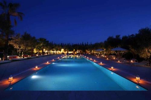 a large swimming pool with lights at night at Le Bled Ferme in Marrakech