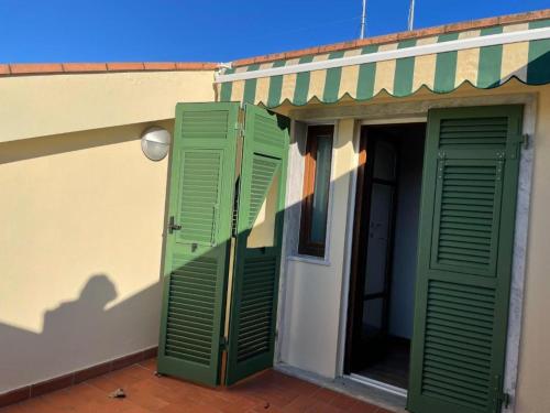 a building with green shutters on the side of it at Confortevole camera matrimoniale con terrazza a 500 mt dal mare in Marina di Carrara