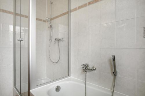 a bathroom with a shower and a white tub at Hotel Garni Vitamari in Wasserburg am Bodensee