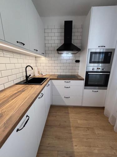a kitchen with white cabinets and a sink and a stove at City Heart Luxury Apartment in Nové Zámky