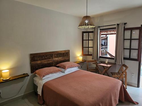 a bedroom with a bed and a table and a window at Pousada do Alferes in Paty do Alferes