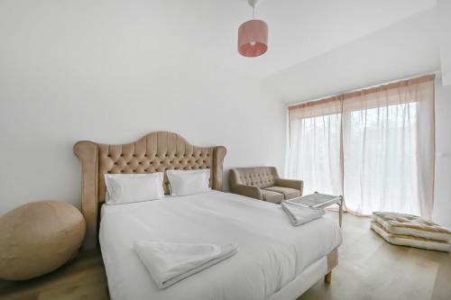 une chambre blanche avec un grand lit blanc et une fenêtre dans l'établissement La Douce Escapade - 6 pers - Jardin - Wifi, à Évreux