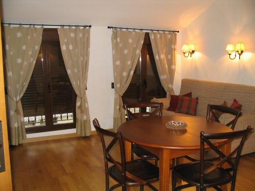 a dining room with a table and chairs and a couch at Villa Russell Hotel&Apartments in Torla