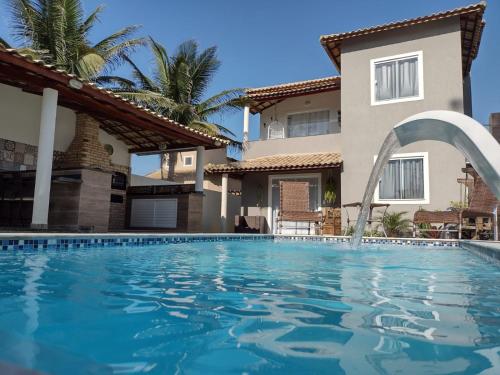 a swimming pool in front of a house at Espaço Long Beach - Cabo Frio in Cabo Frio