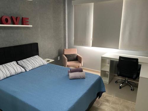 a bedroom with a blue bed and a chair at Espaço Long Beach - Cabo Frio in Cabo Frio