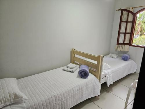 two twin beds in a room with a window at Pousada do Alferes in Paty do Alferes