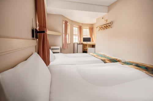 a row of four white beds in a room at Hakuba Sun Valley Hotel in Hakuba