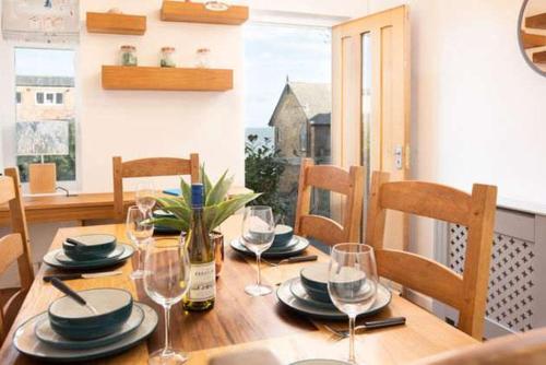 a wooden table with wine glasses and plates on it at Beach Approach House - 30 steps from beach - Luxury house - kids slide and chill-out room - amazing location - garden in Filey