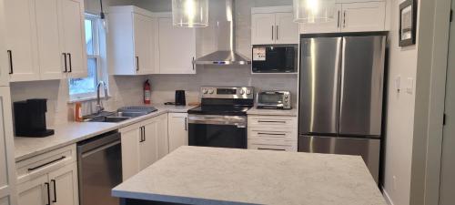 a kitchen with white cabinets and a stainless steel refrigerator at Charm meets North in Moncton