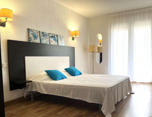 een slaapkamer met een groot bed met 2 blauwe kussens bij SAINT FLORENT - Studio 3 pers balcon vue mer FLO127 in Saint-Florent