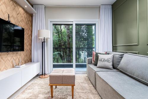 a living room with a gray couch and a large window at Apartamento Wunderhaus Luxo by Achei in Canela