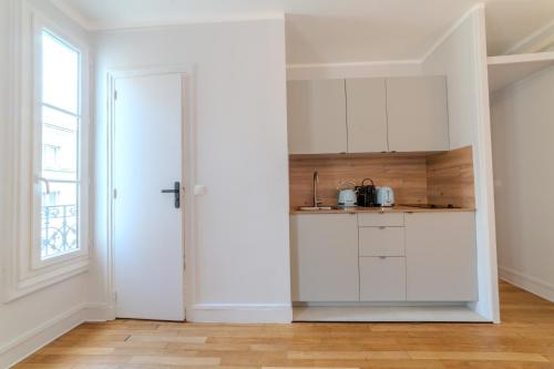 une cuisine avec des placards blancs et une porte dans l'établissement Majestic Suite, à Paris
