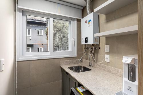 a small kitchen with a sink and a window at Apartamento Wunderhaus Luxo by Achei in Canela