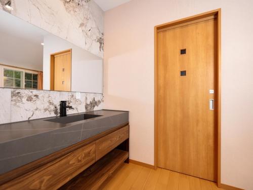 a bathroom with a sink and a wooden door at Hakuba Sun Valley Hotel in Hakuba