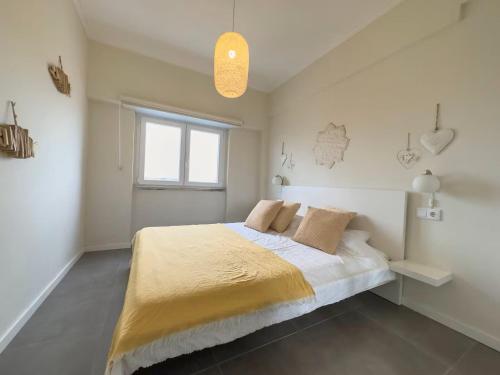 a bedroom with a bed with a yellow blanket and a window at GuestReady - Seaview in Costa da Caparica in Costa da Caparica