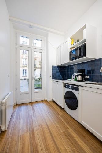 une cuisine avec des armoires blanches et un plancher en bois dans l'établissement 1#Cosystudio#Paris13#JardinDesPlantes, à Paris