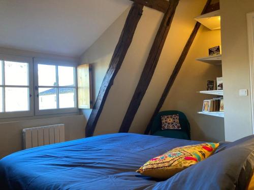 une chambre avec un lit bleu et deux fenêtres dans l'établissement Duplex-Au château ambulant-au bord de la Dordogne, à Castelnaud-la-Chapelle