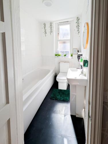 a bathroom with a tub and a toilet and a sink at Cozy 2BR Flat Near Twickenham Stadium for Families in Teddington