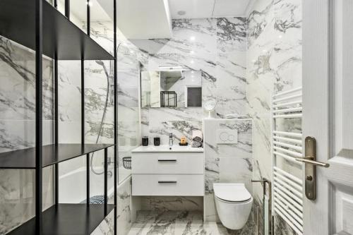 La salle de bains est pourvue de murs en marbre, de toilettes et d'un lavabo. dans l'établissement Gold Queen, à Cannes