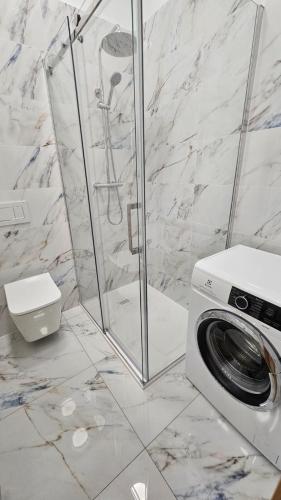 a bathroom with a shower and a washing machine at byt 69m2 na Trzni kolonáde in Karlovy Vary