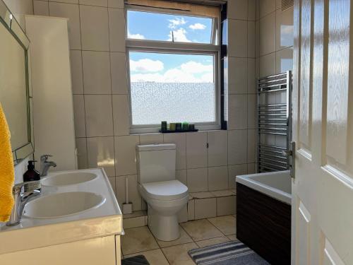 a bathroom with a sink and a toilet and a window at LARGE bedroom SINGLE bed in Feltham