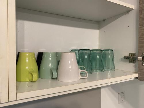 a shelf with different colored glass vases on it at Cozy Emira Home 3 Bedrooms in Shah Alam