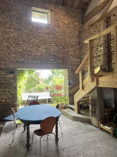 un patio avec une table et des chaises et un mur de briques dans l'établissement L'Alcôve, maison d'artistes, à Sacquenay