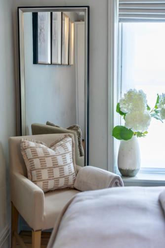 a bedroom with a chair and a vase with flowers in a window at Danes Cottage - Luxury Peak District Retreat in Chapel en le Frith