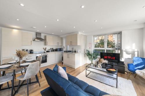 a living room with a blue couch and a kitchen at 2 BDR, Wembley Stadium, Parking, Family Friendly in London