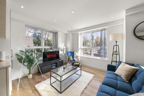 a living room with a blue couch and a tv at 2 BDR, Wembley Stadium, Parking, Family Friendly in London