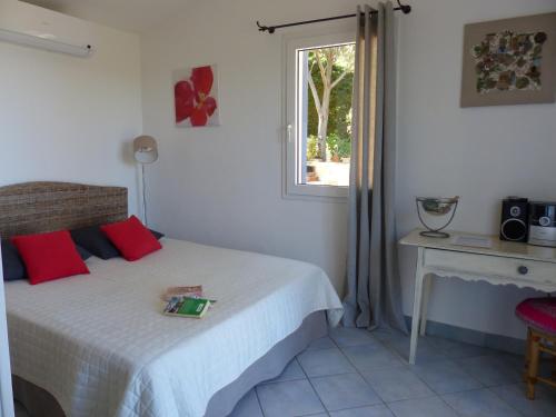 une chambre avec un lit avec des oreillers rouges et une fenêtre dans l'établissement Palmier, à Corbara