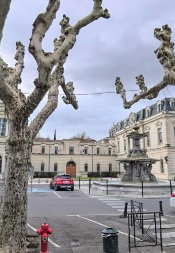 une voiture rouge garée dans un parking en face d'un bâtiment dans l'établissement L'Espi - Hyper centre Montélimar, à Montélimar