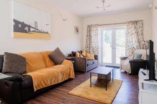 a living room with a couch and a table at Spacious 6 bedroom House in Dudley with optional Nursery-Drive and Garage-Families and Contractors Welcome in Tipton