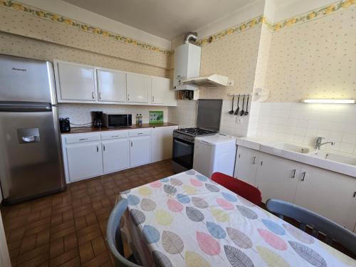 - une cuisine avec des placards blancs, une table et un réfrigérateur dans l'établissement Appartement cosy à l'Harteloire, à Brest