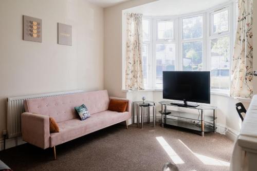 a living room with a couch and a television at Spacious 6 bedroom House in Dudley with optional Nursery-Drive and Garage-Families and Contractors Welcome in Tipton