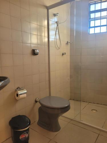 a bathroom with a toilet and a glass shower at Quartos Itapê in Itapetininga