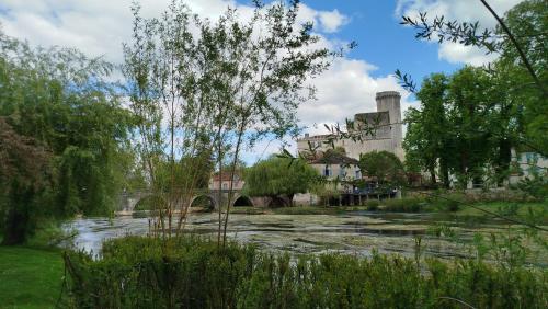une rivière avec un pont et un bâtiment en arrière-plan dans l'établissement Studio indépendant au calme, à Château-lʼÉvêque
