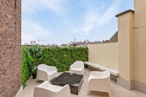 un patio con sedie bianche e un tavolo su un edificio di Luxe Stay in Heart of Mechelen a Mechelen